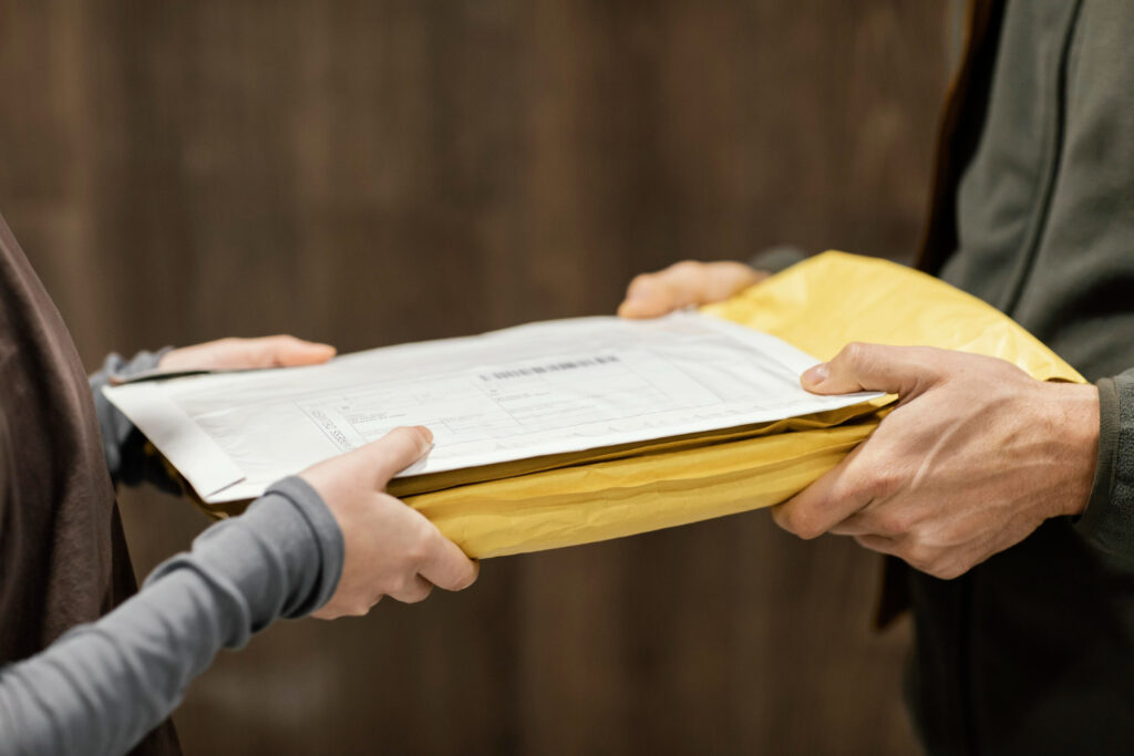 Close-up of a package being handed off between two individuals during formal document delivery