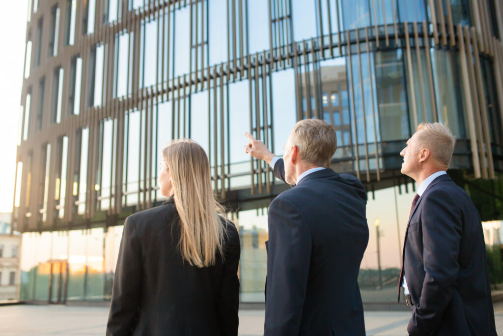 Three business professionals observing a modern office building during daylight