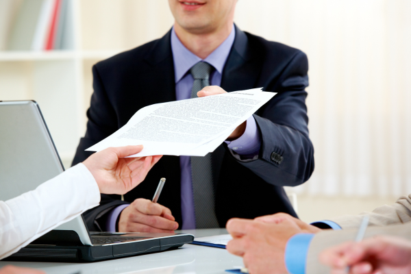 Process server handing legal documents to a client during a formal business meeting, demonstrating professional document delivery services